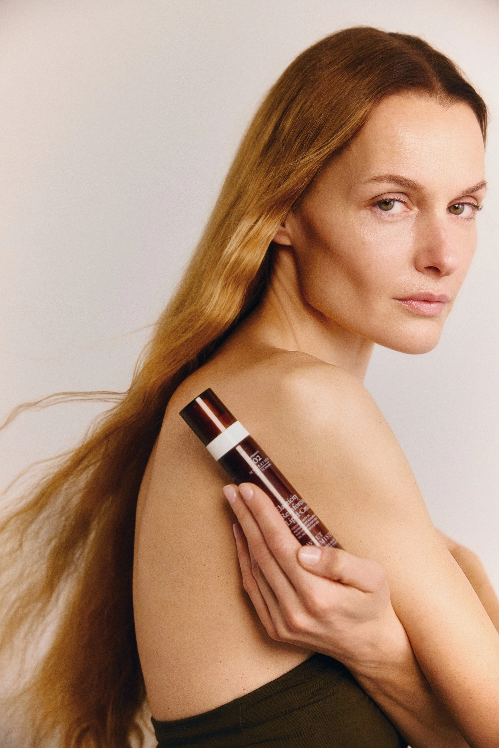 Woman holding a Sweet Chemistry bottle against her shoulder